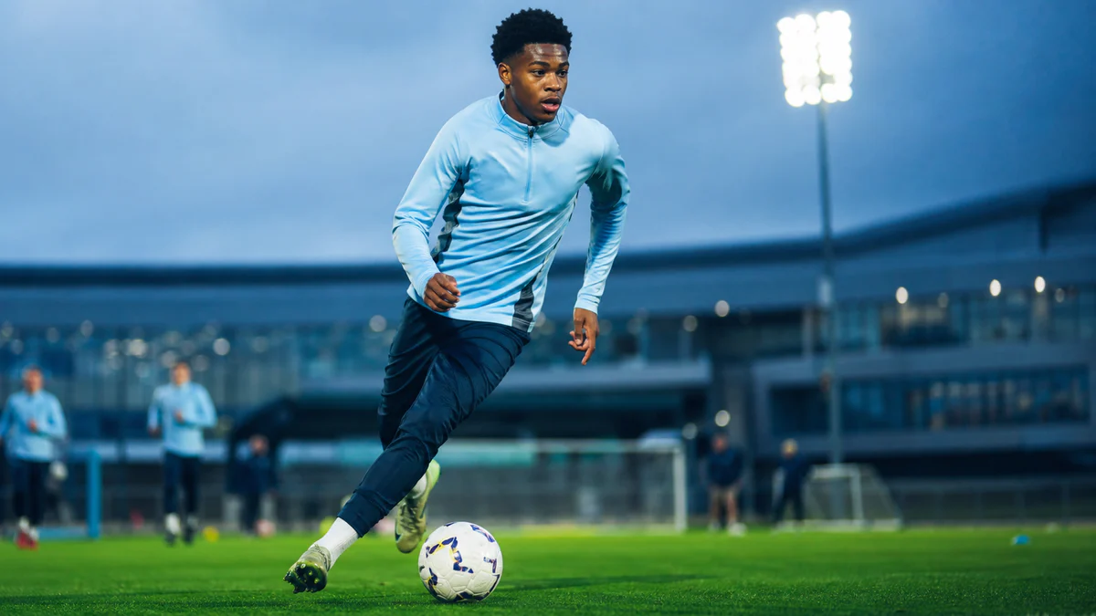 Editorial illustration of Jeremy Monga dribbling at a modern training ground